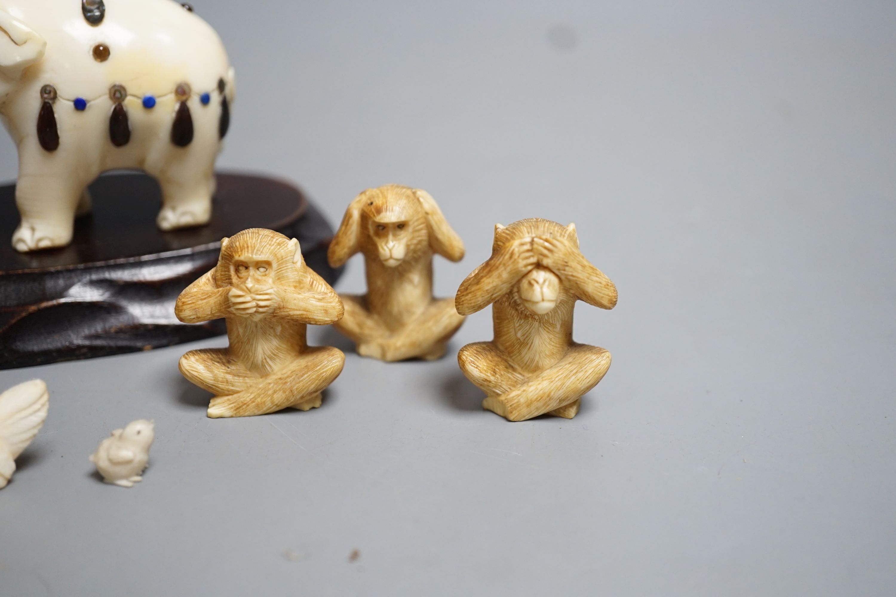 A Japanese Ivory and Shibayama style model of an elephant, three Japanese Ivory figures of the three wise monkeys and three Japanese ivory models of chickens and a chick, wood stand, all late 19th/early 20th century